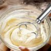Home baker using the manual mixer to blend cream and flour for a perfect batter