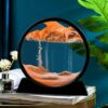 Circular kinetic sand art piece with orange sand on a black stand atop a stack of books